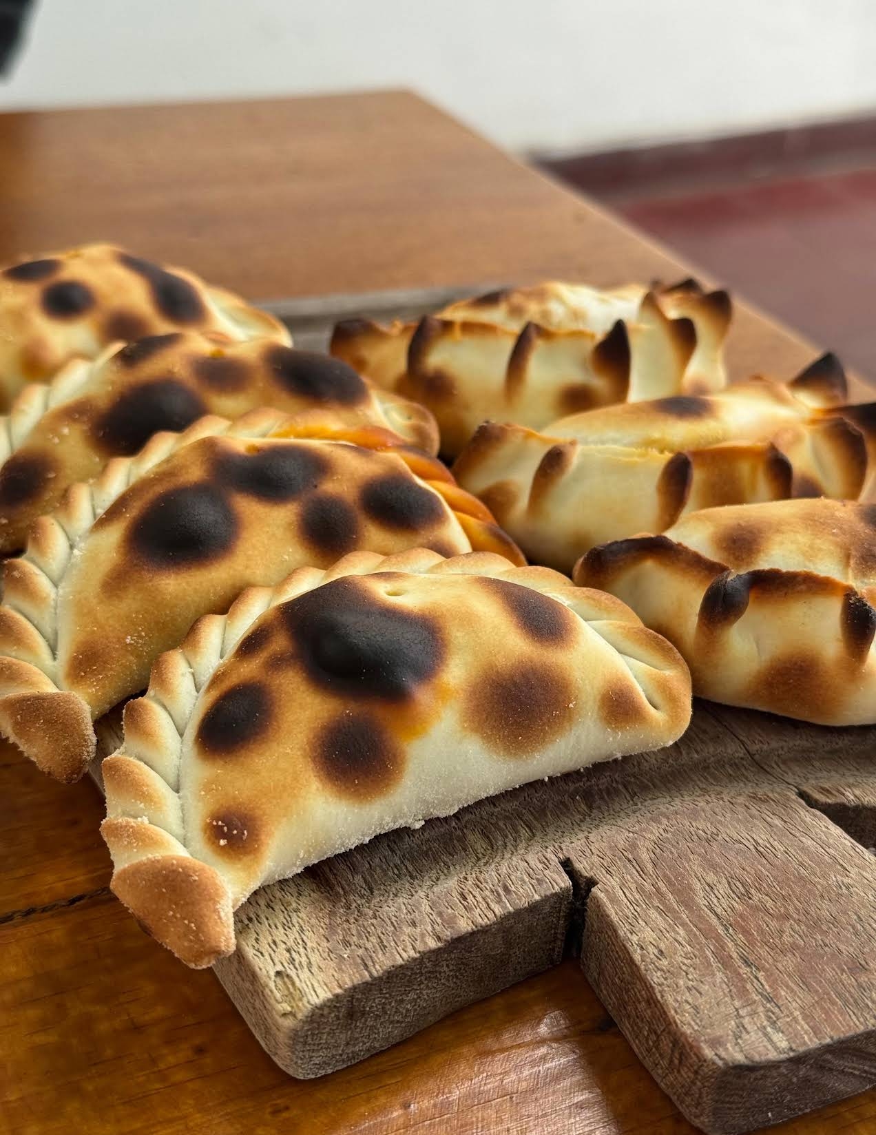 Freshly baked Salteña empanadas on a wooden board